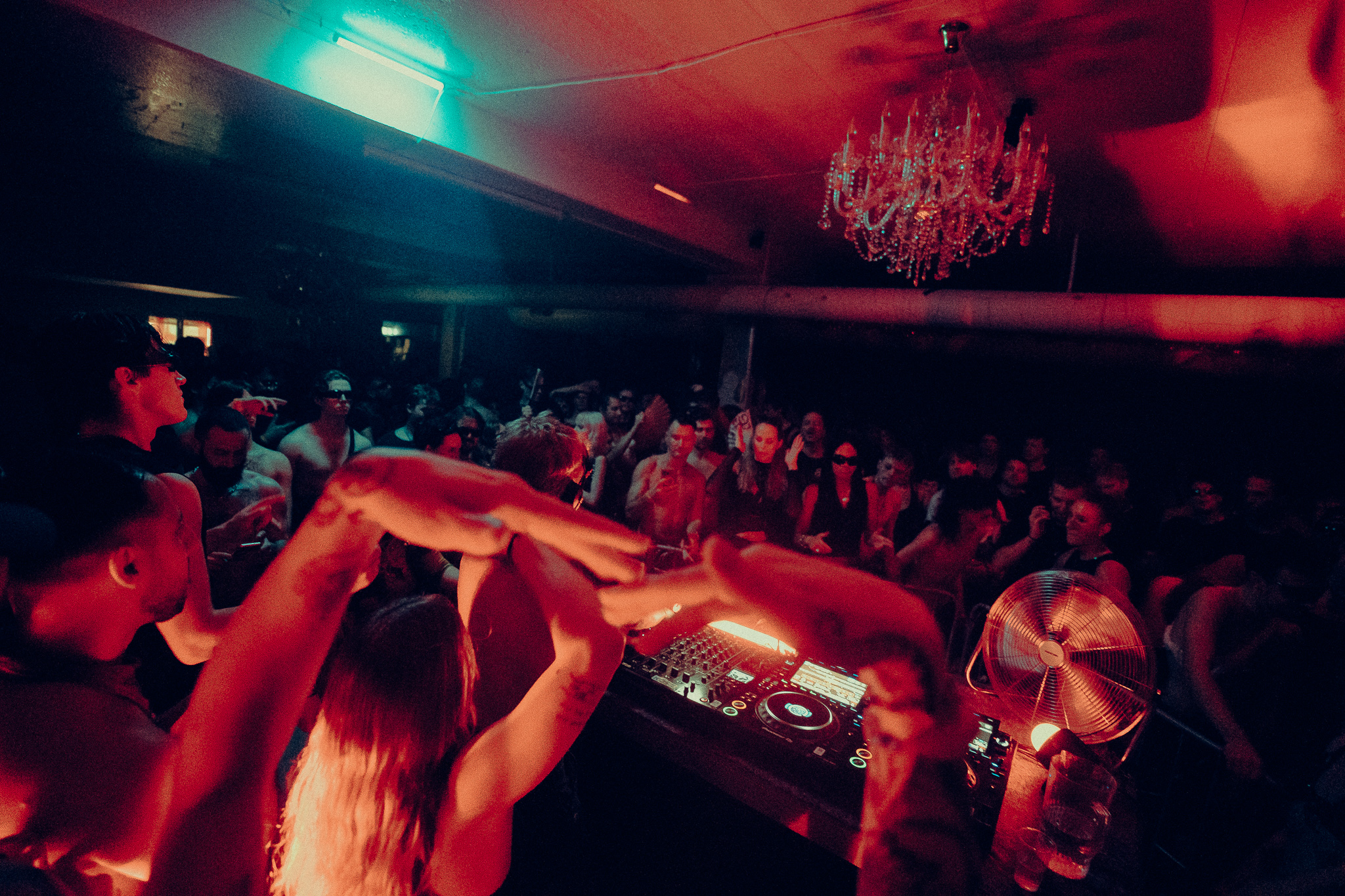 A dancer holding a white fan above the crowd in teal light