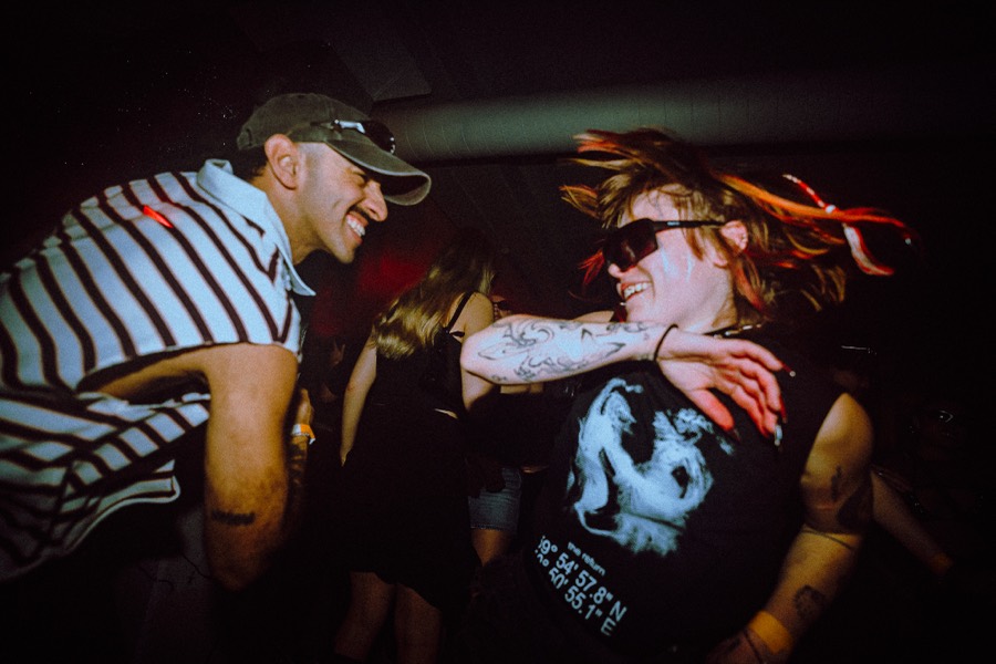 Two people laughing together in the middle of the crowd