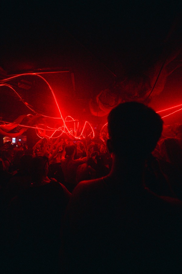 A figure silhouetted in the crowd against red neon